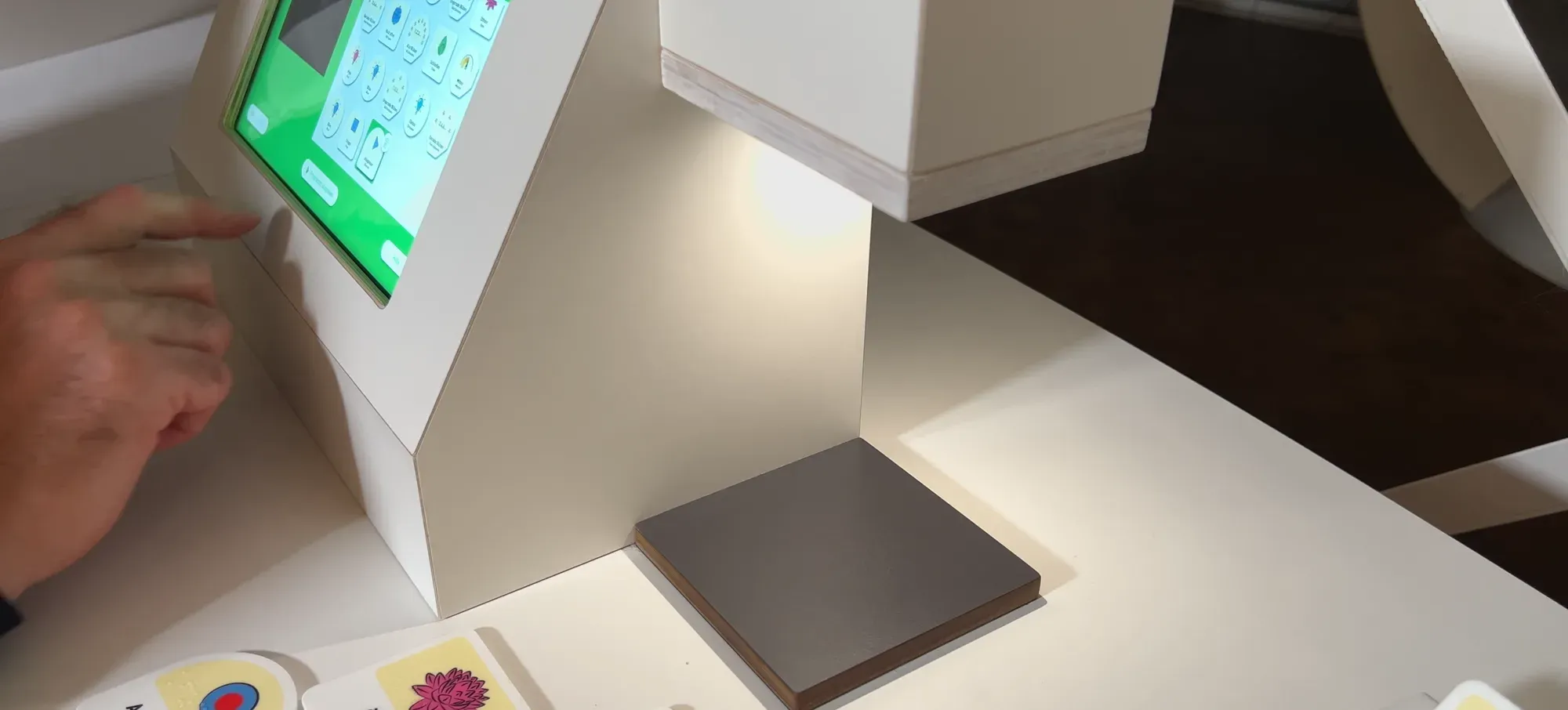 The tablet showing the grid of commands, with the grey scanning pad and two cards on the counter below it