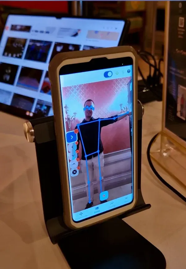 The training app on a phone on a stand, showing a man as a stick figure with one arm stretched out
