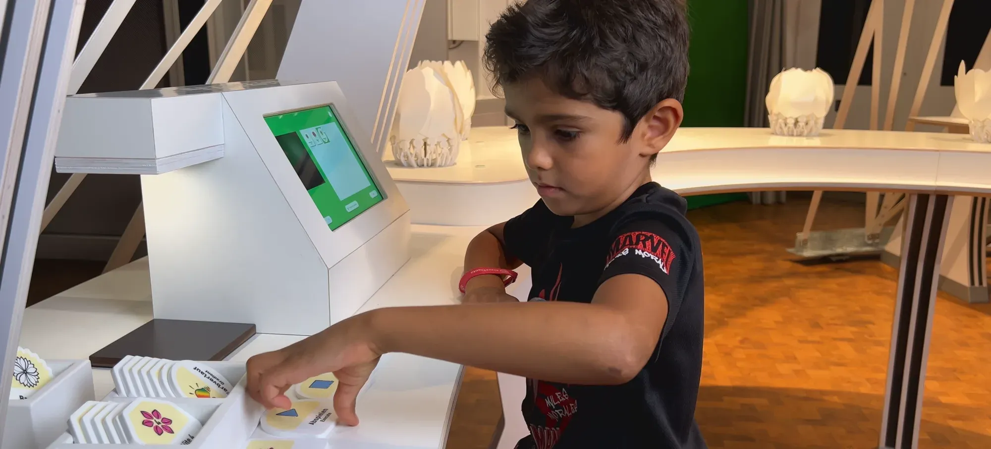 A boy reaching into the trays of programming cards next to the station’s tablet
